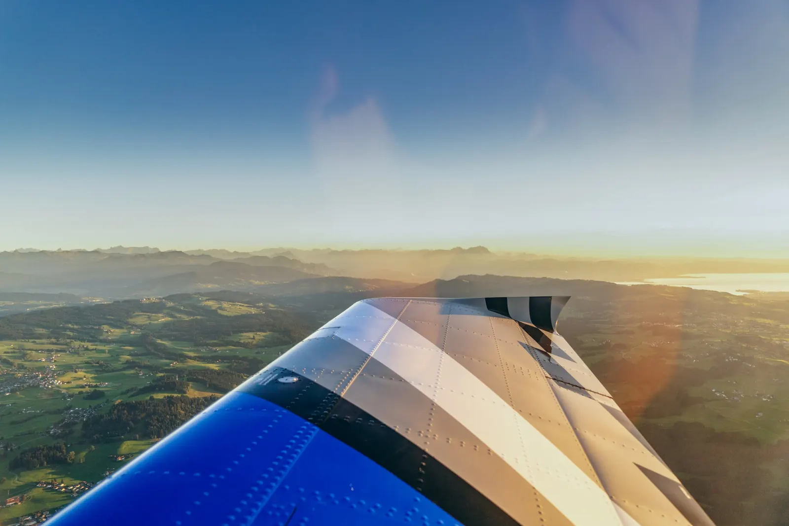 Tragfläche im Gegenlicht der Abendsonne über einer weiten Landschaft